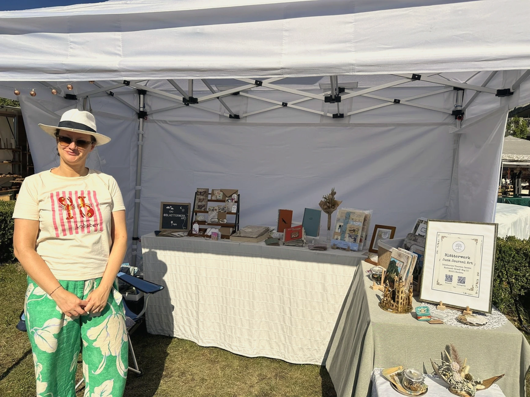 Inhaberin von Blätterwerk, Therese, auf dem Kunsthandwerkermarkt in Füssen vor ihrem Marktstand mit Junk Journals.